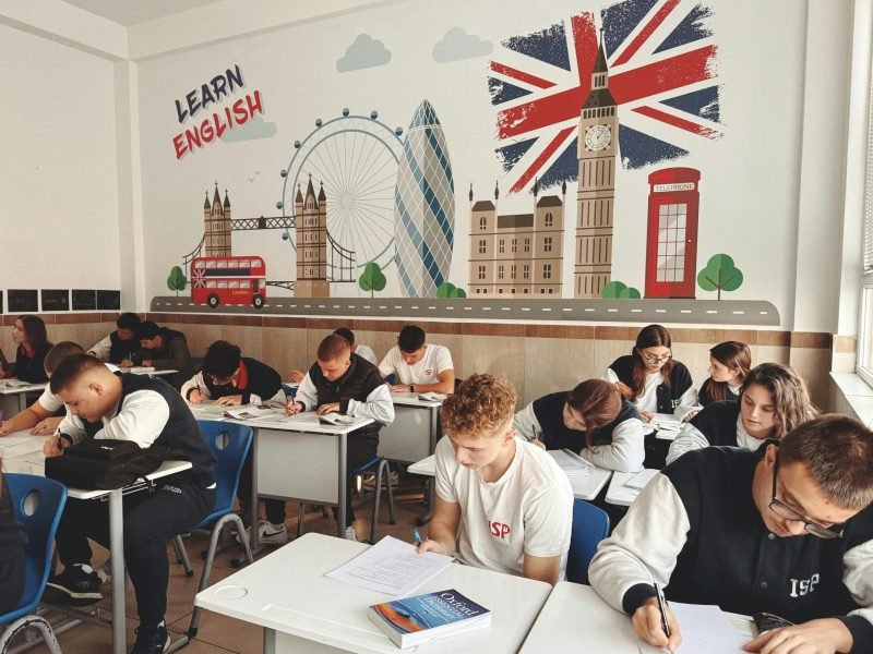 Students studying English in a classroom with British themed decor and mural.